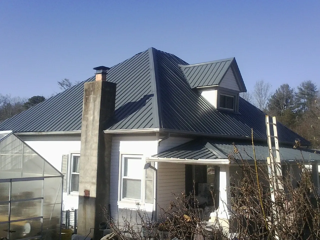 Dark blue standing seam metal roof on a white farmhouse with dormer — Slate & Tile Roof Repair by Roofing Brothers in Hansville