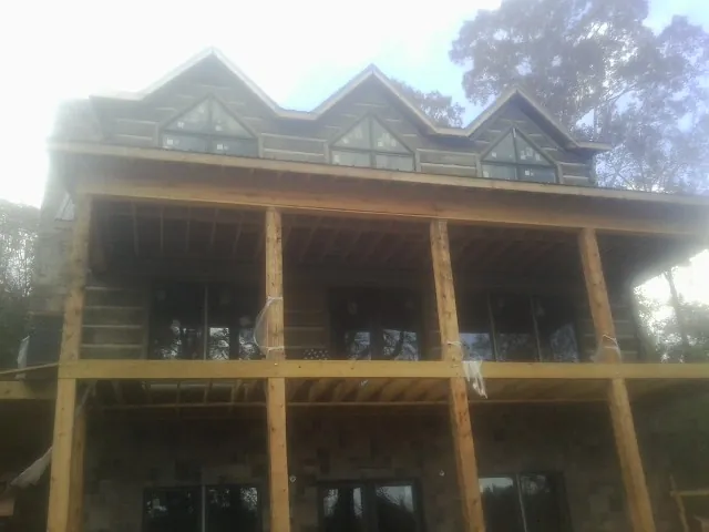Dormers and porch framing on a large log home under construction — Roof Coating work by our crew in Hansville