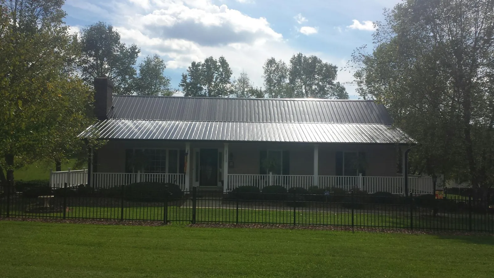 Gray metal roof on a brick ranch with a full width front porch — Gutter Guard Installation work by our crew in Hansville