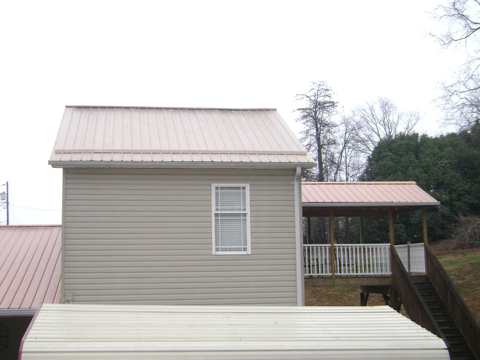 Tan metal roofs on a two story addition and attached porch, from a Roof Replacement job in Hansville