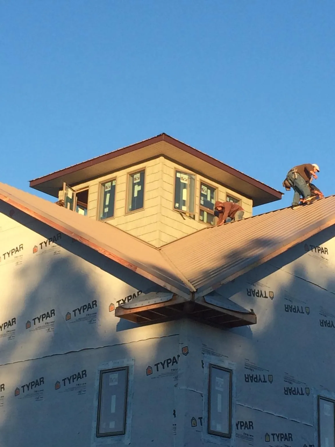 Roofers working around a rooftop cupola on a new metal roof at sunset — Roof Waterproofing in Hansville by Roofing Brothers